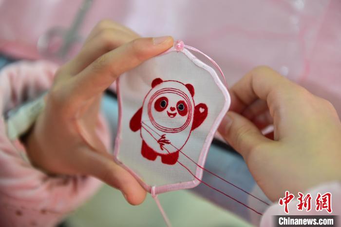圖為一名小學(xué)生正在繡制2022年北京冬奧會(huì)吉祥物“冰墩墩”形象?！∮髟屏?攝