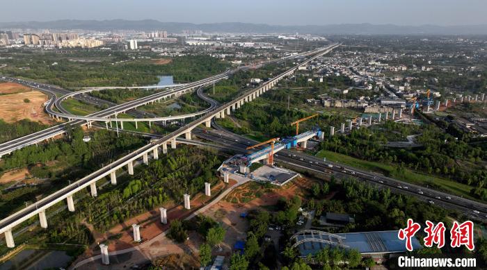 航拍正在建設的跨越成都繞城高速公路連續(xù)梁施工現(xiàn)場，旁邊依次為已運營的成渝高速鐵路和機場高速公路?！⒅铱?攝