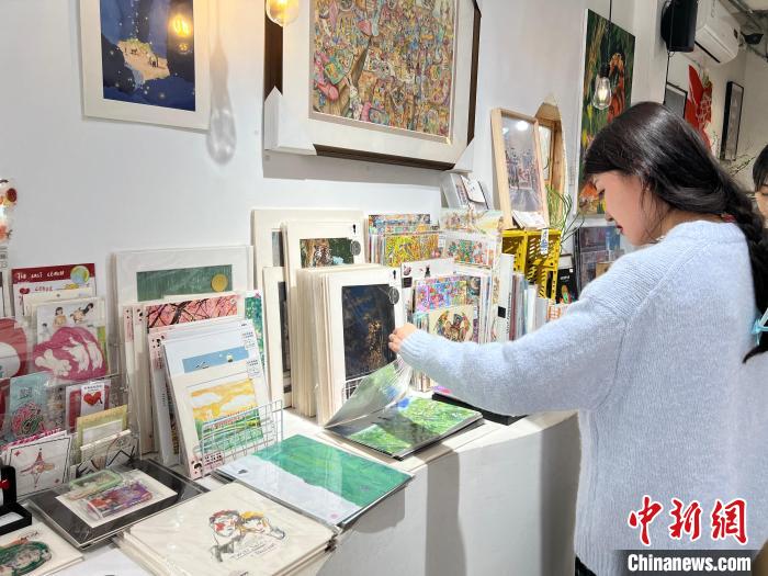 圖為藝術(shù)品商店內(nèi)，顧客挑選插畫作品?！＄婌?攝