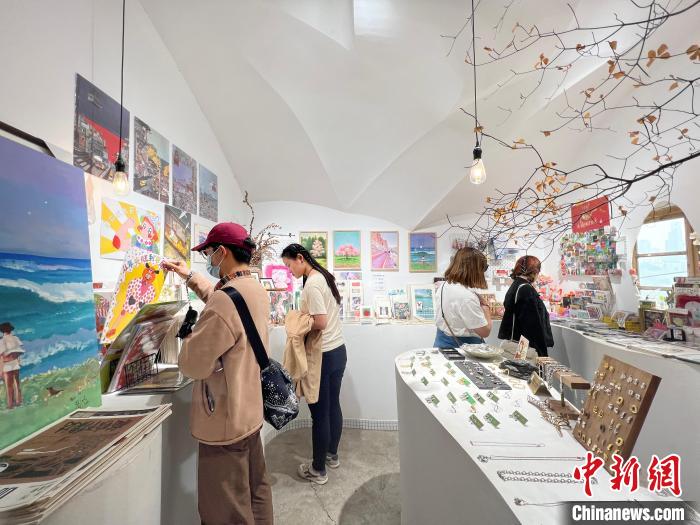 圖為藝術(shù)品商店內(nèi)，顧客挑選插畫作品?！＄婌?攝