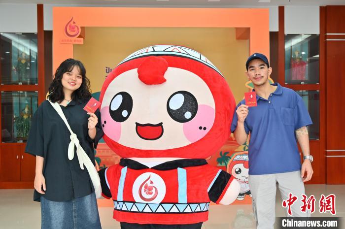 圖為泰國(guó)留學(xué)生手持獻(xiàn)血證與人偶合影?！∮峋?攝