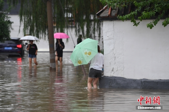 7月31日，市民行走在雨中的北京房山區(qū)瓦窯頭村。北京市氣象臺當(dāng)日10時發(fā)布分區(qū)域暴雨紅色預(yù)警信號。北京市水文總站發(fā)布洪水紅色預(yù)警，預(yù)計當(dāng)日12時至14時，房山區(qū)大石河流域?qū)⒊霈F(xiàn)紅色預(yù)警標(biāo)準(zhǔn)洪水。<a target='_blank' href='/'><p  align=