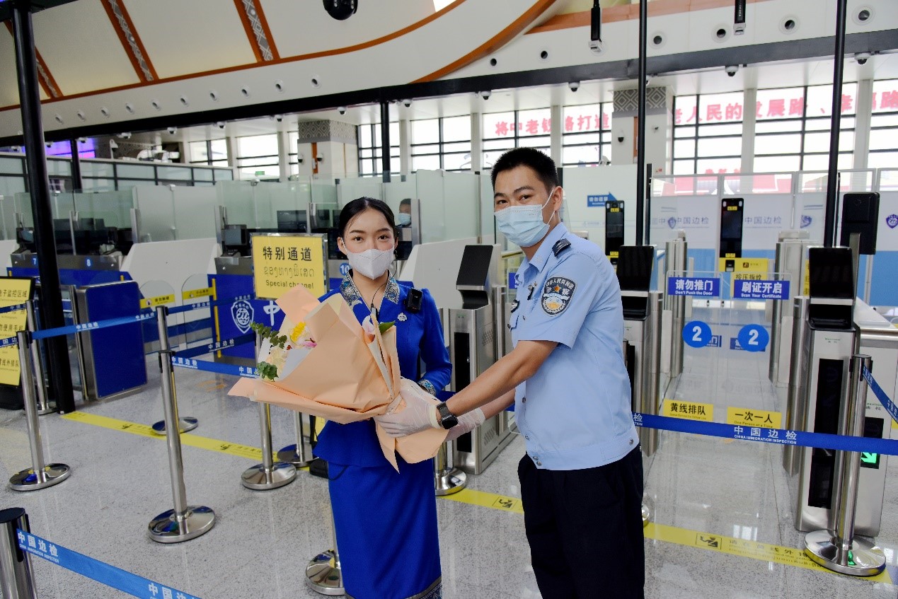 磨憨出入境邊防檢查站民警為中老鐵路第100萬名出入境旅客，D888次國際旅客列車?yán)蠐爰藙?wù)員森達(dá)拉·妮緹婭（Sengdala Nitiya），送上鮮花。黃遠(yuǎn)飛 攝