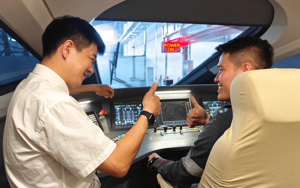 8月25日，在印度尼西亞萬隆的雅萬高鐵德卡魯爾動車所內(nèi)，中國師傅穆振（左）在向印尼火車司機塞蒂亞萬講解動車組出庫前的上電作業(yè)。