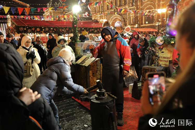 游客在新年集市上體驗制作紀(jì)念幣。人民網(wǎng)記者 隋鑫攝
