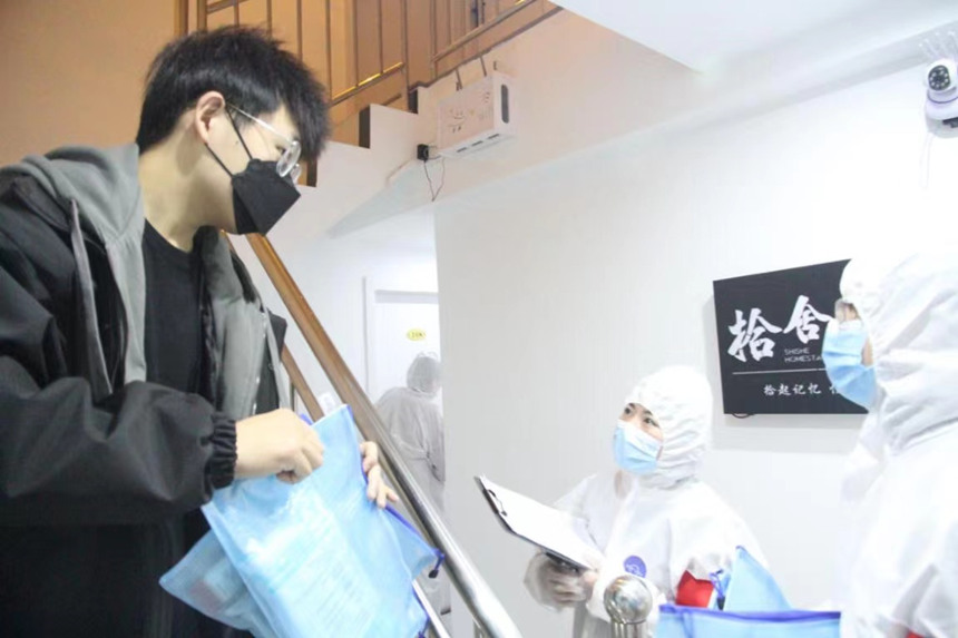 社區(qū)工作人員和志愿者身穿防護服上門送馬應(yīng)龍大健康防疫包。徐帥攝