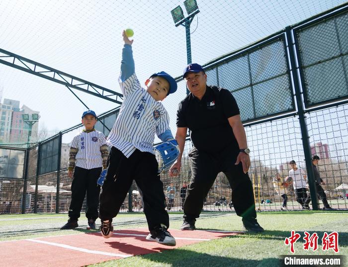 圖為來自臺灣的棒球教練劉興鴻(右)指導(dǎo)小棒球手?jǐn)S球技術(shù)?！●R銘言 攝