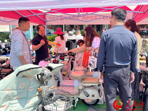 某電動(dòng)自行車品牌工作人員向消費(fèi)者介紹以舊換新相關(guān)情況。人民網(wǎng)記者 杜燕飛攝