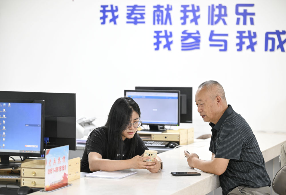 2024年6月20日，在寧夏銀川市金鳳區(qū)長城花園社區(qū)黨群服務(wù)中心，工作人員幫助居民辦理業(yè)務(wù)。圖片來源 新華社