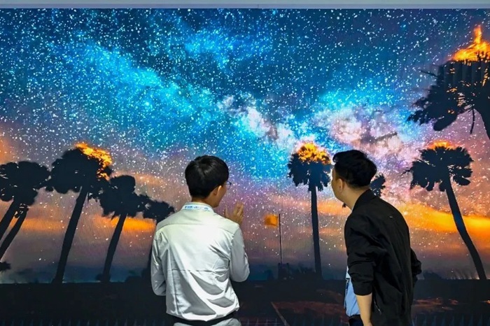 長春光博會希達(dá)電子展區(qū)，一位工作人員正在給一位觀眾講解。（長春新區(qū)供圖）