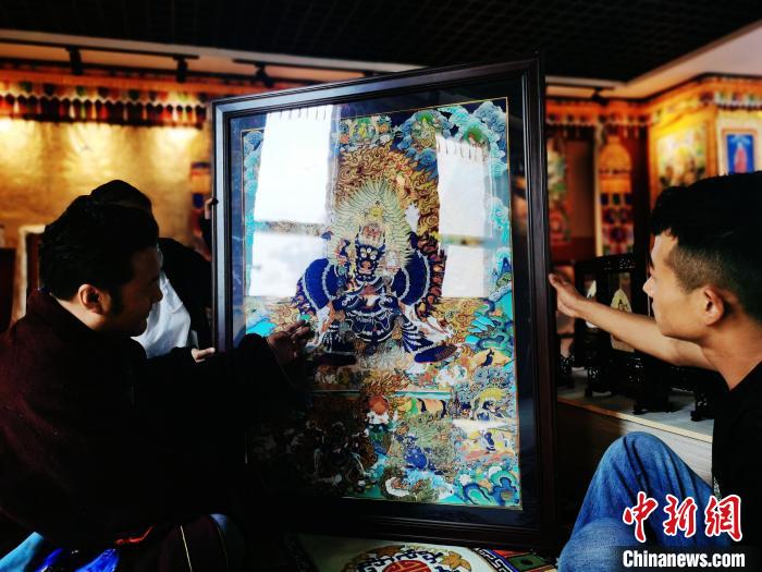 圖為久美尖措(左)與徒弟們展示唐卡作品。　張?zhí)砀?攝