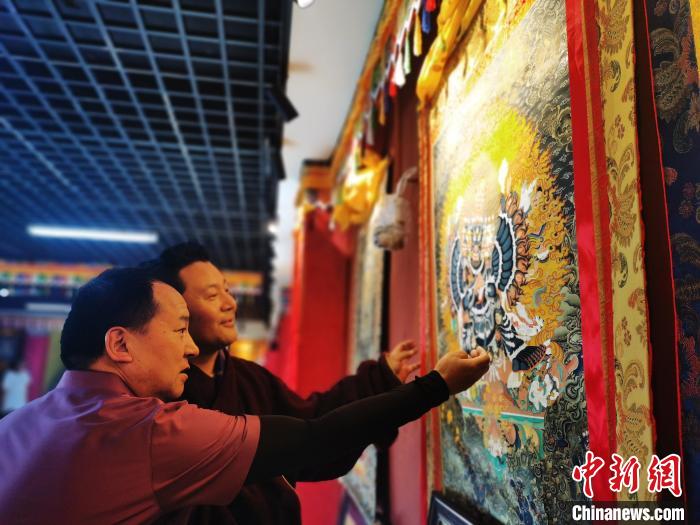 圖為久美尖措展示唐卡作品?！?zhí)砀?攝