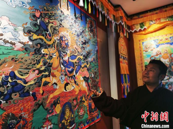 圖為久美尖措展示唐卡作品?！?zhí)砀?攝