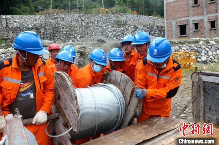 國網四川送變電公司搶險隊員將重達370公斤的鋼絞線搬上車?！⑾驸C 攝