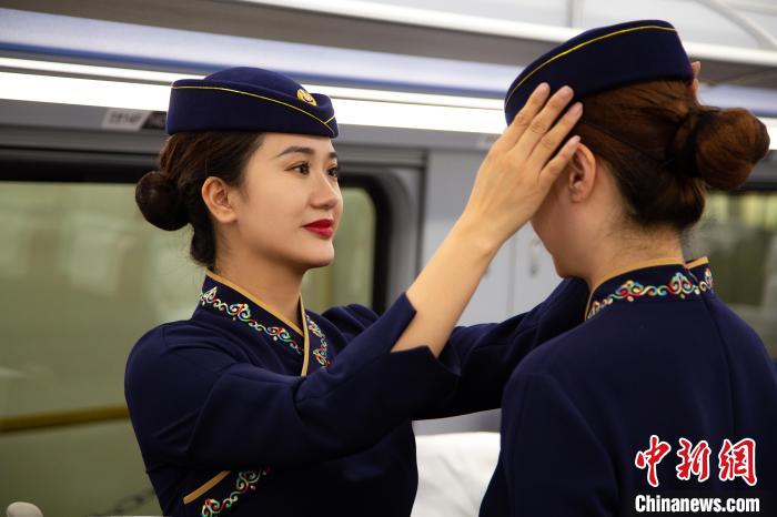 圖為青藏鐵路西格段“復(fù)興號(hào)”動(dòng)車(chē)組乘務(wù)員互相整理新制服。　李磊 攝