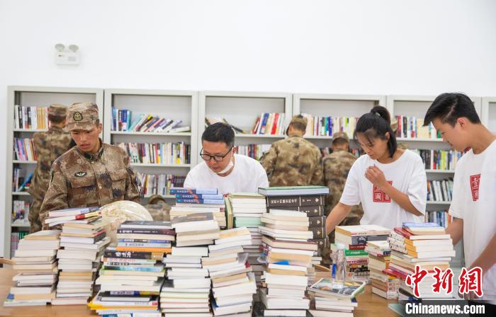 圖為志愿者們和邊防戰(zhàn)士整理圖書?！詵| 攝