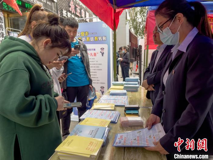 圖為工作人員正在向路過市民介紹國家反詐中心軟件的功能?！≈x牧 攝