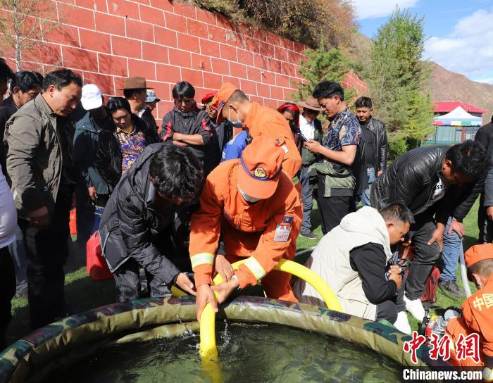 圖為森林消防員為護(hù)林員講解滅火裝備的使用方法?！〔际猩窒乐ш?duì) 供圖