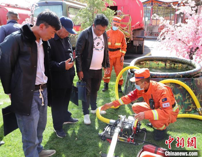 圖為森林消防員為護(hù)林員講解滅火裝備的使用方法?！〔际猩窒乐ш?duì) 供圖