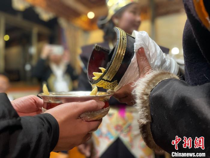 圖為主人在碗中斟滿青稞酒?！∪轿木?攝