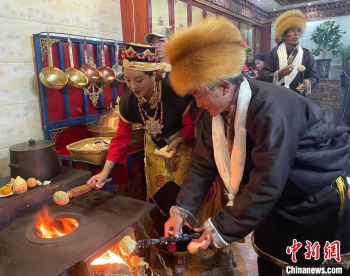 圖為人們在火上烤節(jié)日美食“結(jié)達”?！∪轿木?攝