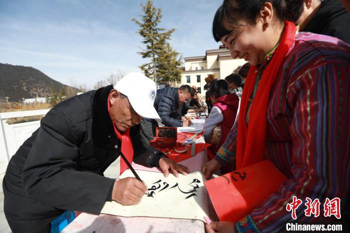 圖為林芝市文聯(lián)書(shū)法家協(xié)會(huì)會(huì)員向民眾贈(zèng)送藏文書(shū)法作品?！埩?攝