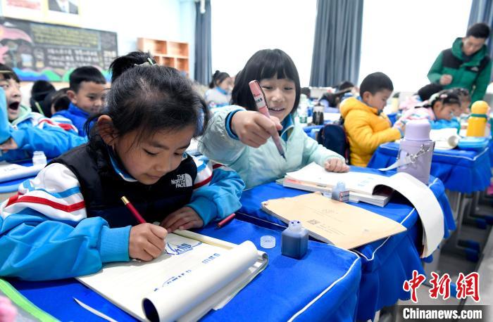 3月14日，西藏拉薩市第一小學一年級六班學生白瑪朗珍(圖左)在藏語文課上書寫藏文。　李林 攝