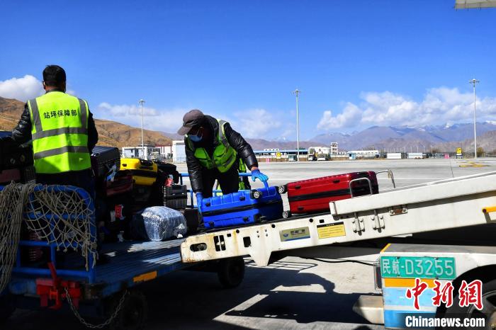 圖為機(jī)場工作人員傳送旅客行李箱。　周航 攝
