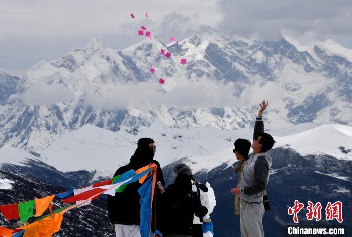 圖為5月14日，游客在西藏林芝色季拉山觀景臺拋灑“隆達”(風(fēng)馬旗，藏族民眾的一種祈福方式)?！±盍?攝